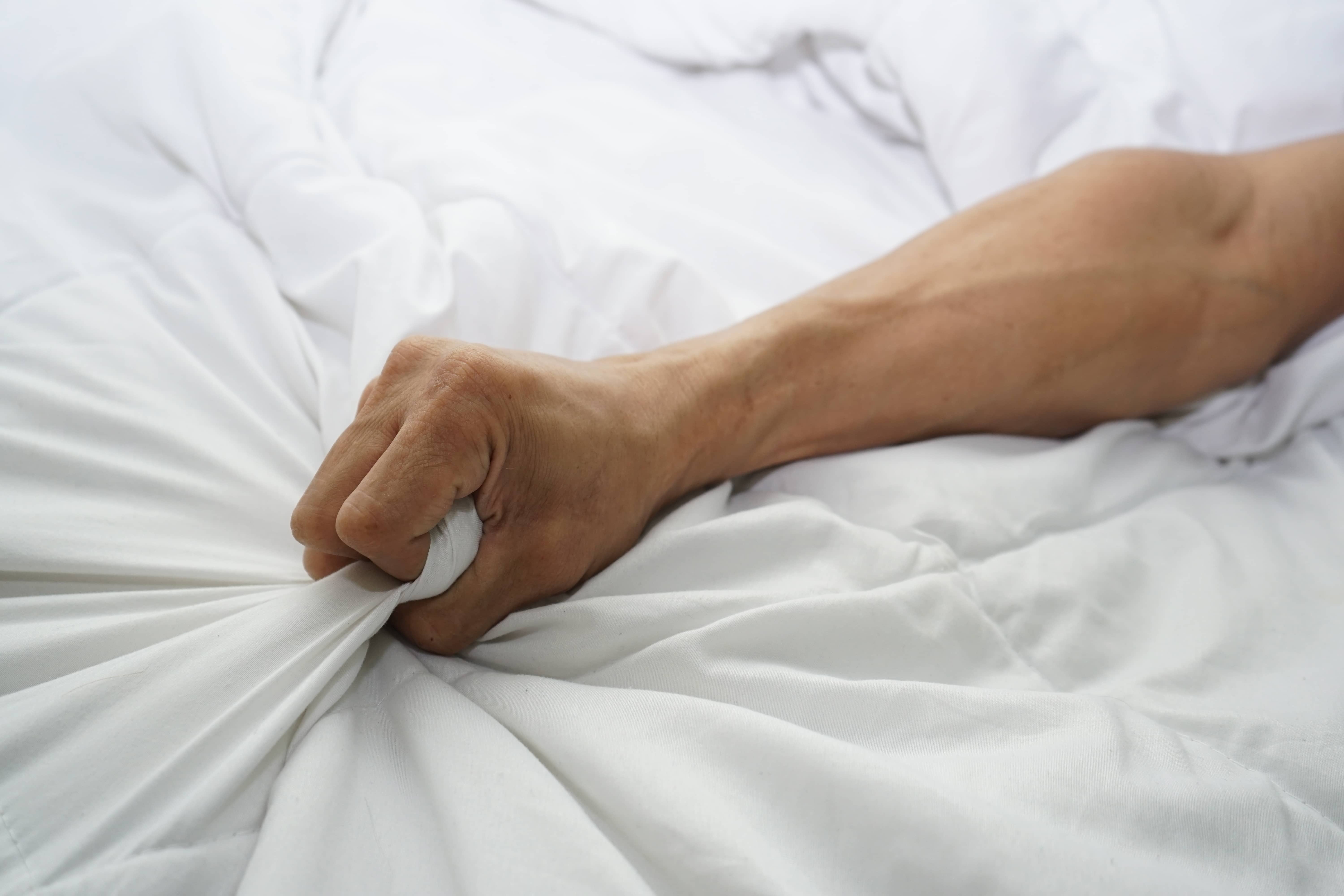 Мужская рука сжимает одеяло